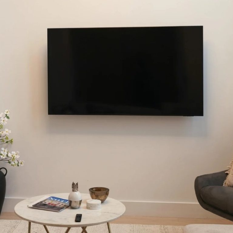 TV streeploos schoon Een moderne woonkamer met een grote, zwarte tv aan de muur en een salontafel.